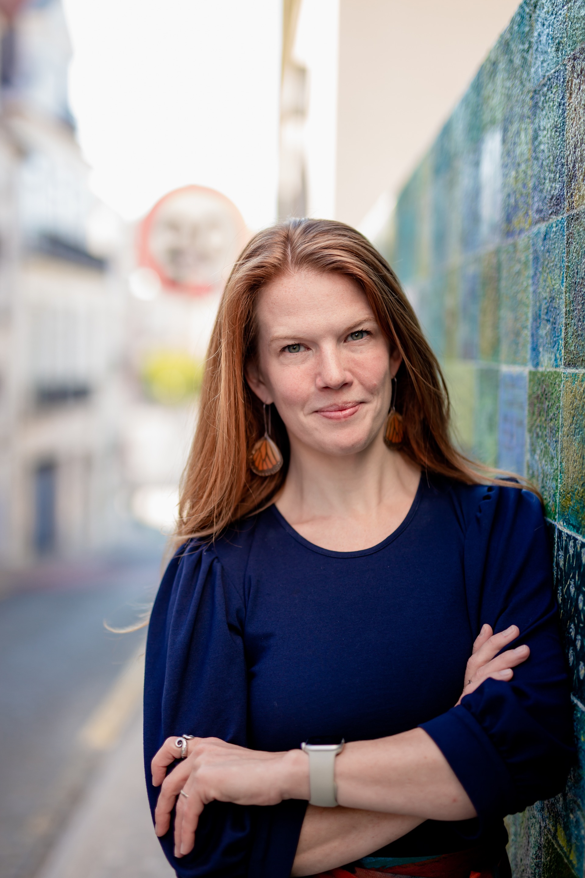 Danielle leaning against a colorful tiled wall